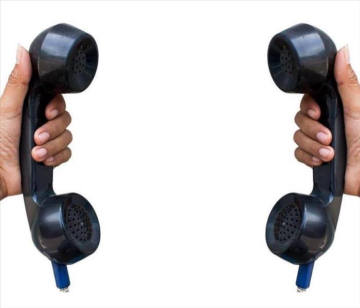 Two hands, each holding black rotary phone sets
